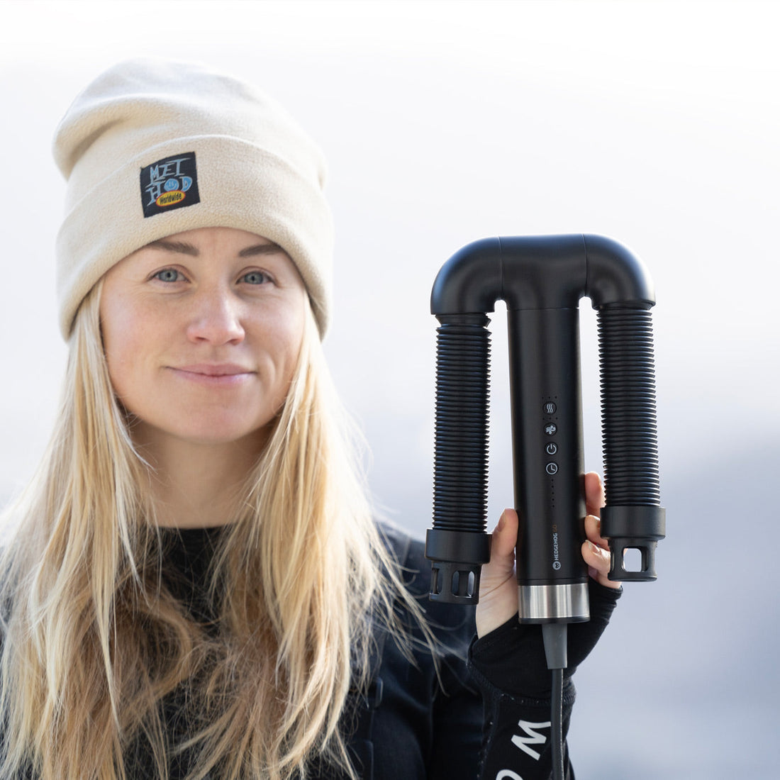 Woman holding Hedgehog GO, dual-purpose hair and boot dryer for travel