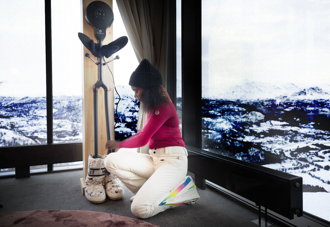 Woman dries snowboard boots and gloves with Hedgehog Dryer Buddy with snowy background